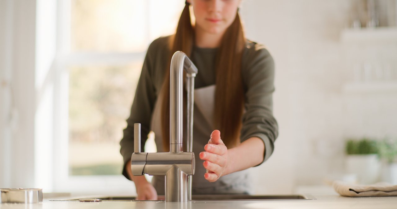 Fille qui prend de l'eau au mitigeur de cuisine avec un capteur