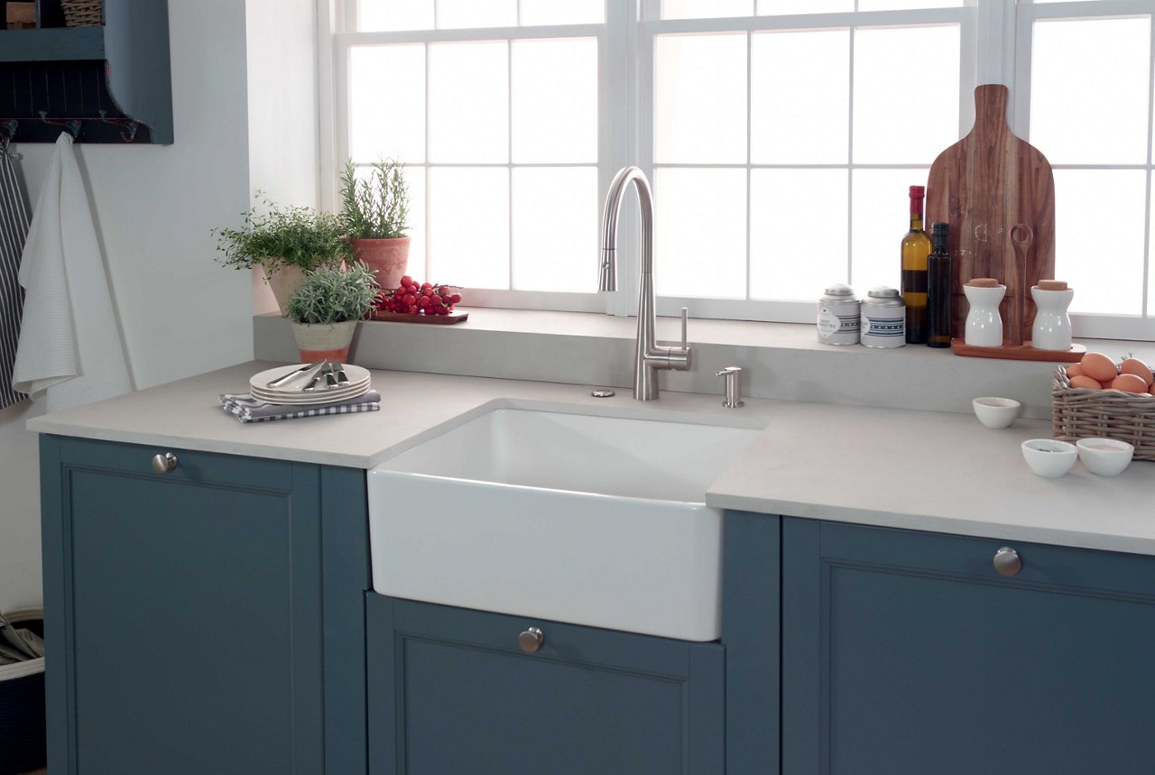 White apron front sink in farmhouse kitchen with blue cabinets
