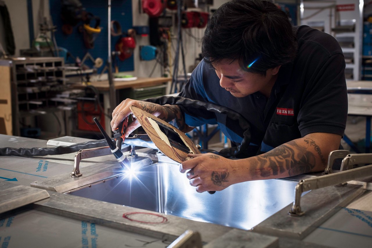 Man welding a Franke sink in a stainless steel worktop