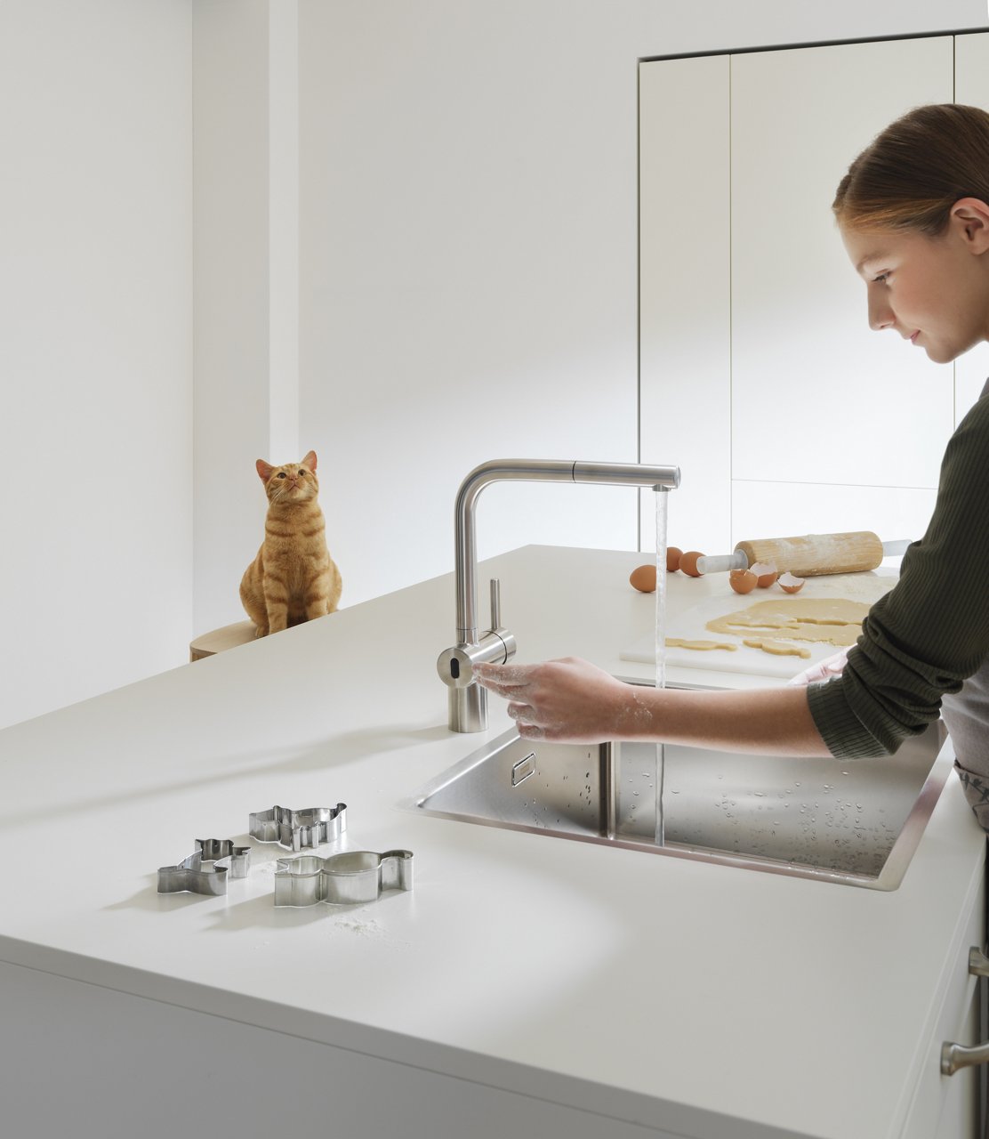 Fille dans une cuisine avec un mitigeur de cuisine avec capteur