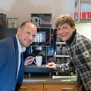 Franke Coffee Systems 2 people standing in front of fully automatic coffee machine Franke, grabbing coffee