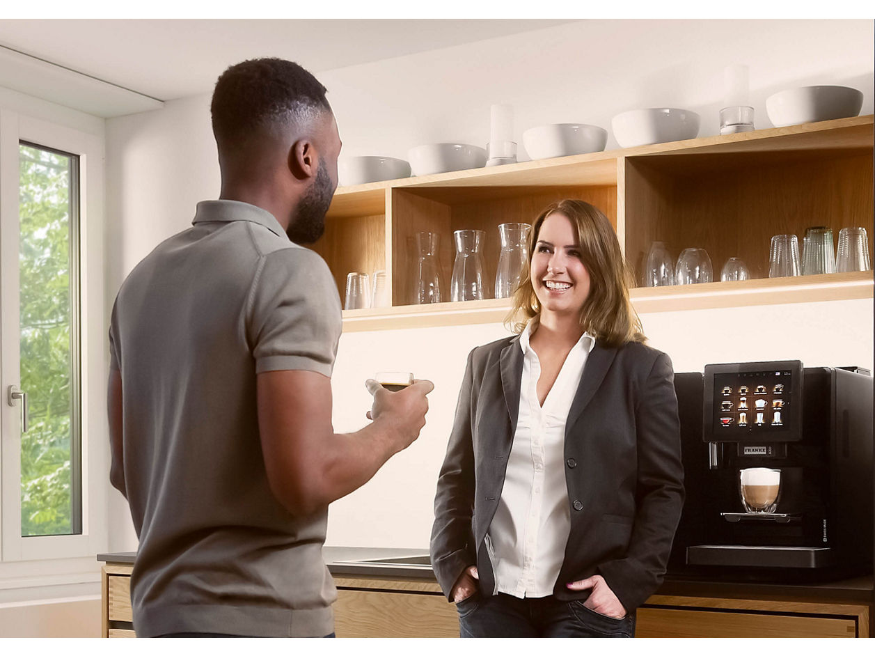 Franke Coffee Systems, man and woman having coffee break in the coffee corner of a workplace, fully automatic coffee machine Franke A300 in the background