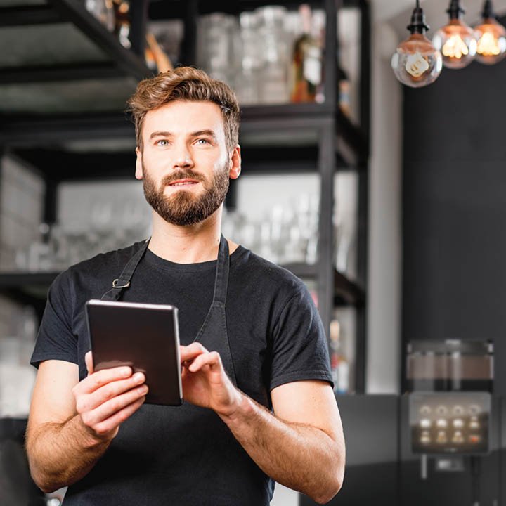 Franke Coffee Systems, waiter holding tablet, fully automatic coffee machine Franke in the background