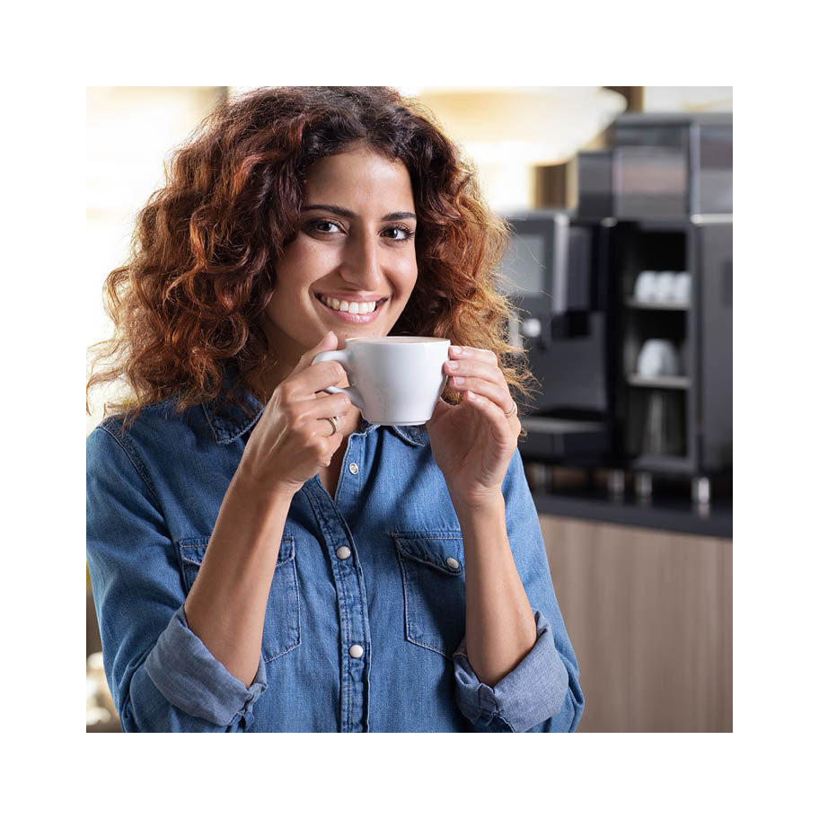 Franke Coffee Systems, italian woman with a smile drinking coffe, fully automatic coffee machine Franke A600 in background