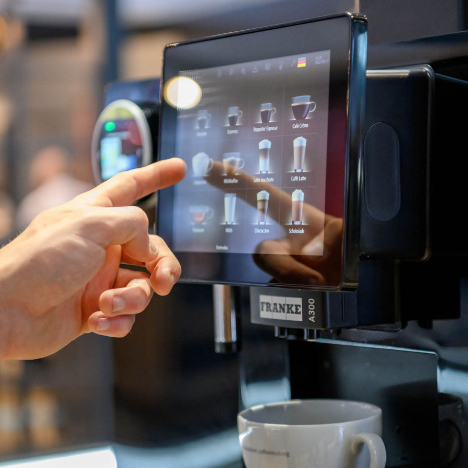 Franke Coffee Systems hand on the coffee machine screen ordering a drink,  fully automatic coffee machine Franke A300