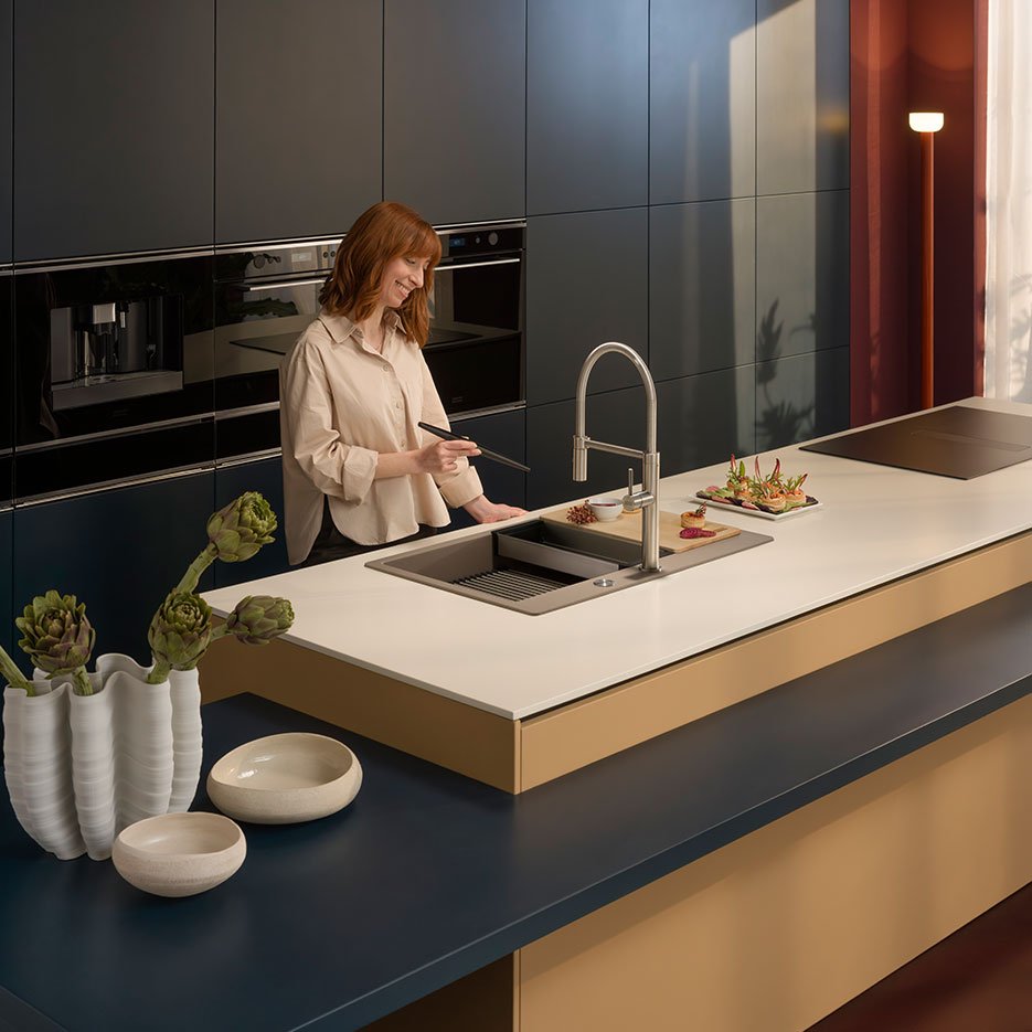 Woman in a kitchen using Franke kitchen sink and tap