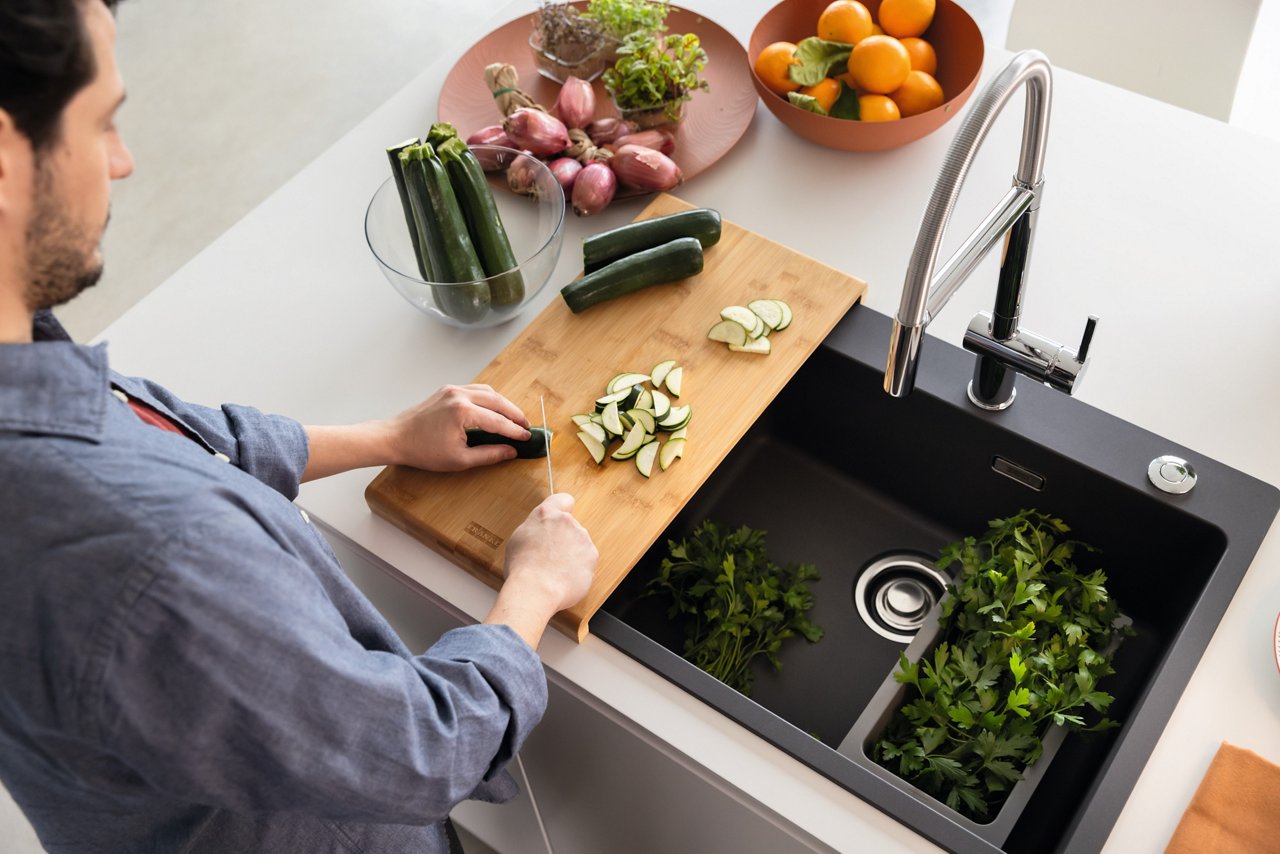 Man chopping vegetables and disposing of waste into a Slimline Elite Food Waste Disposer