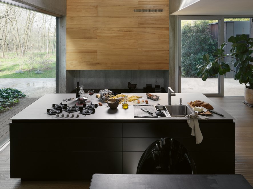 不锈钢操作台面上展示的厨房产品多种多样，从厨房水槽到龙头、从灶具到吸油烟机，应有尽有