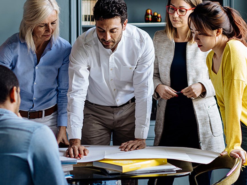 five people standing around a table working