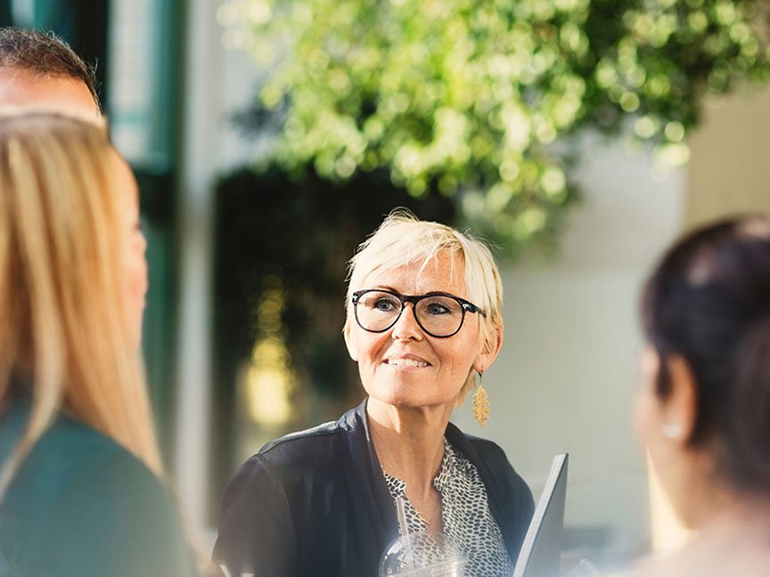 middle aged person outside surrounded by peers