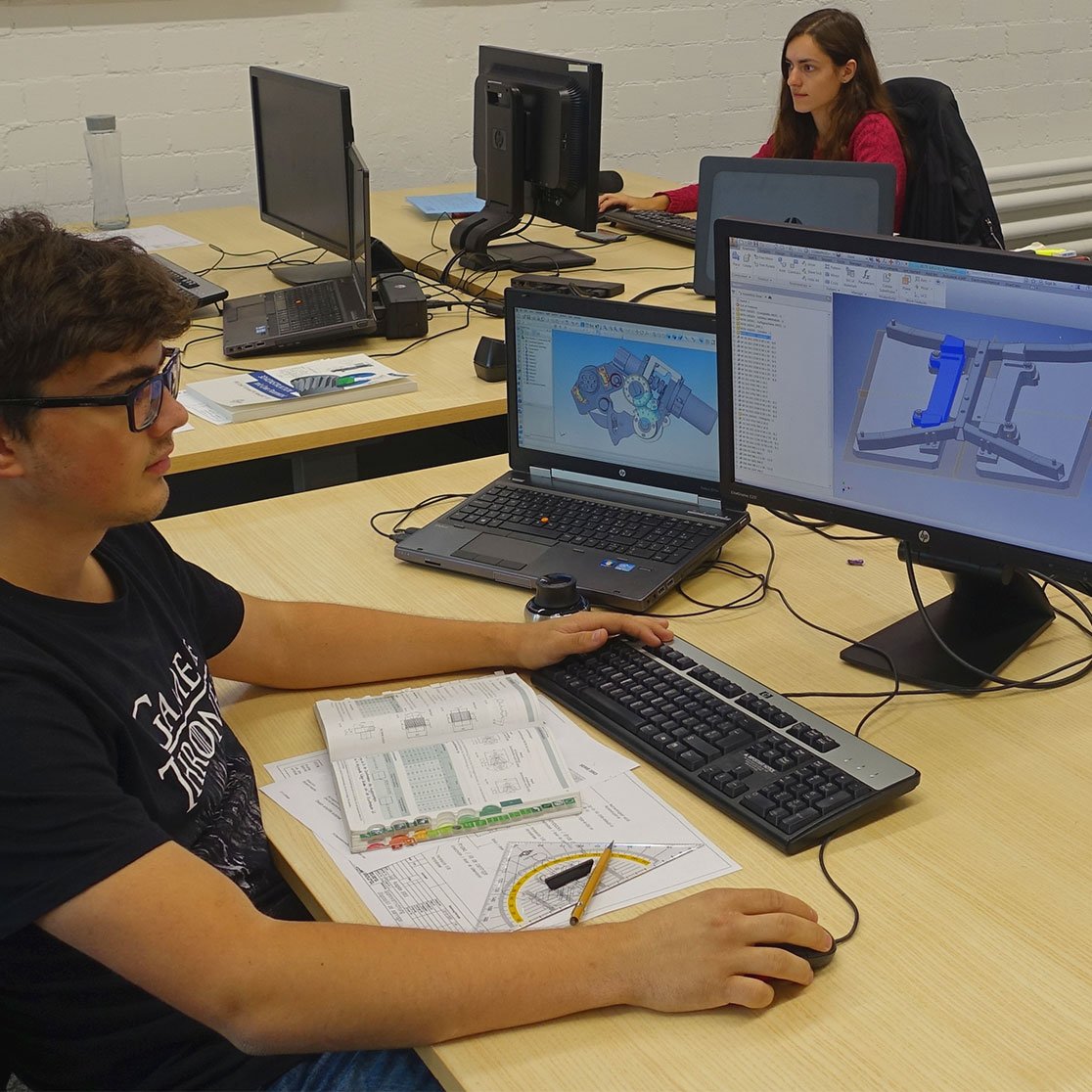 two young persons working on a computer in a office