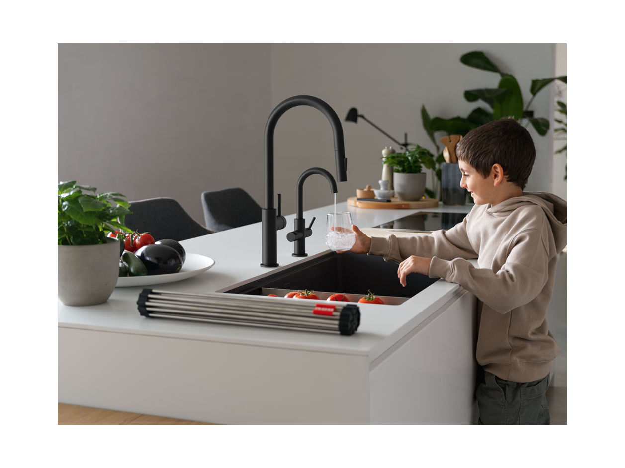 Young child filling a glass with cold filtered water from a Matte black maris lario filtration faucet