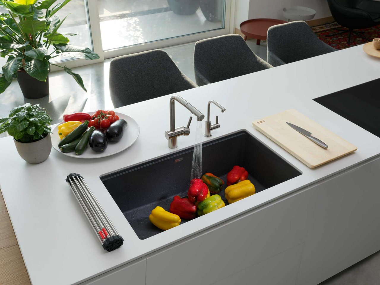 Vegetables being washed in a large undermount black kitchen sink