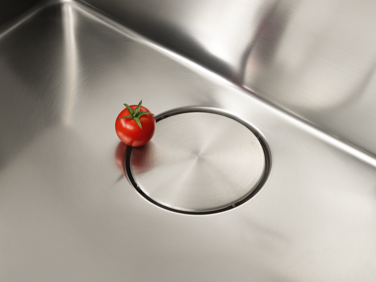 Une tomate à côté de l'égouttoir de l'évier Franke Mythos Bowl