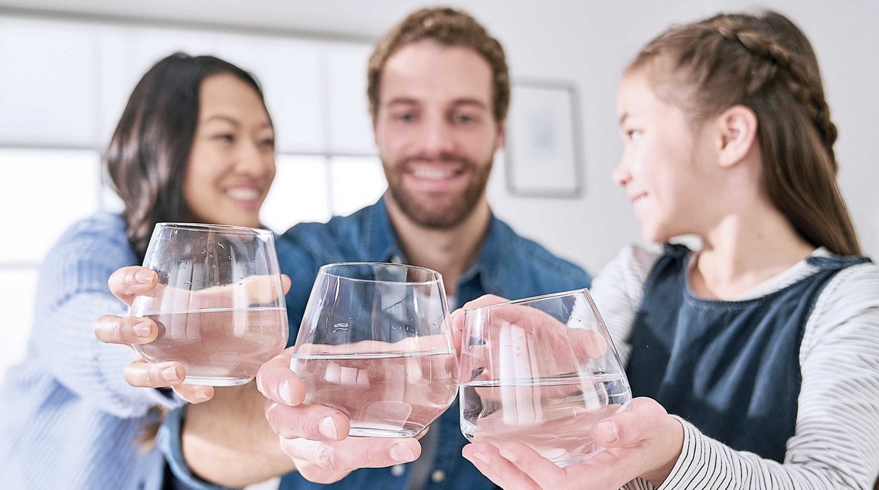 Family cheersing and enjoying clean clear filtered water in water glasses