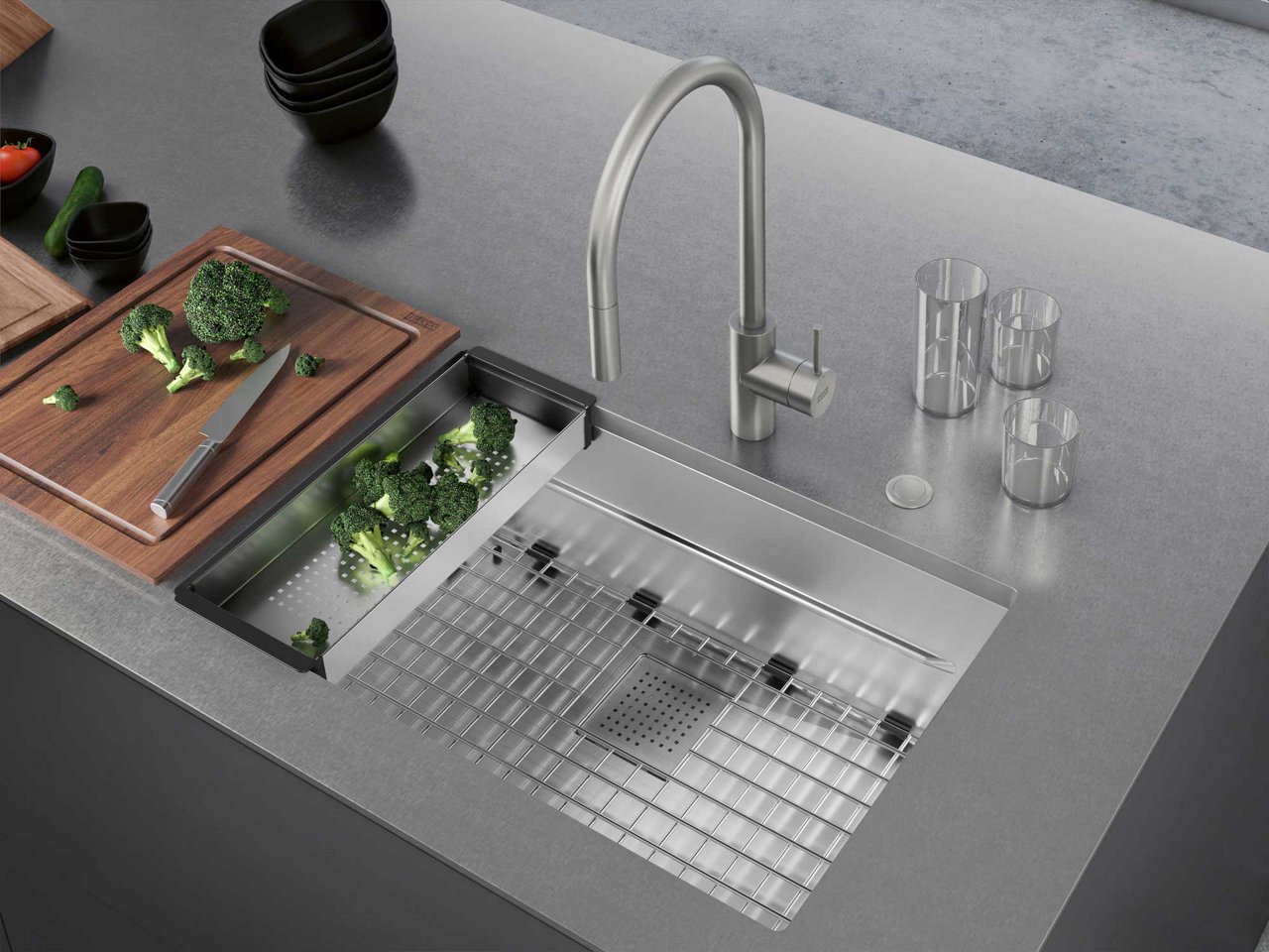 Franke Peak stainless steel single bowl kitchen sink with bottom grid, sink colander and cutting board in a stainless steel countertop 