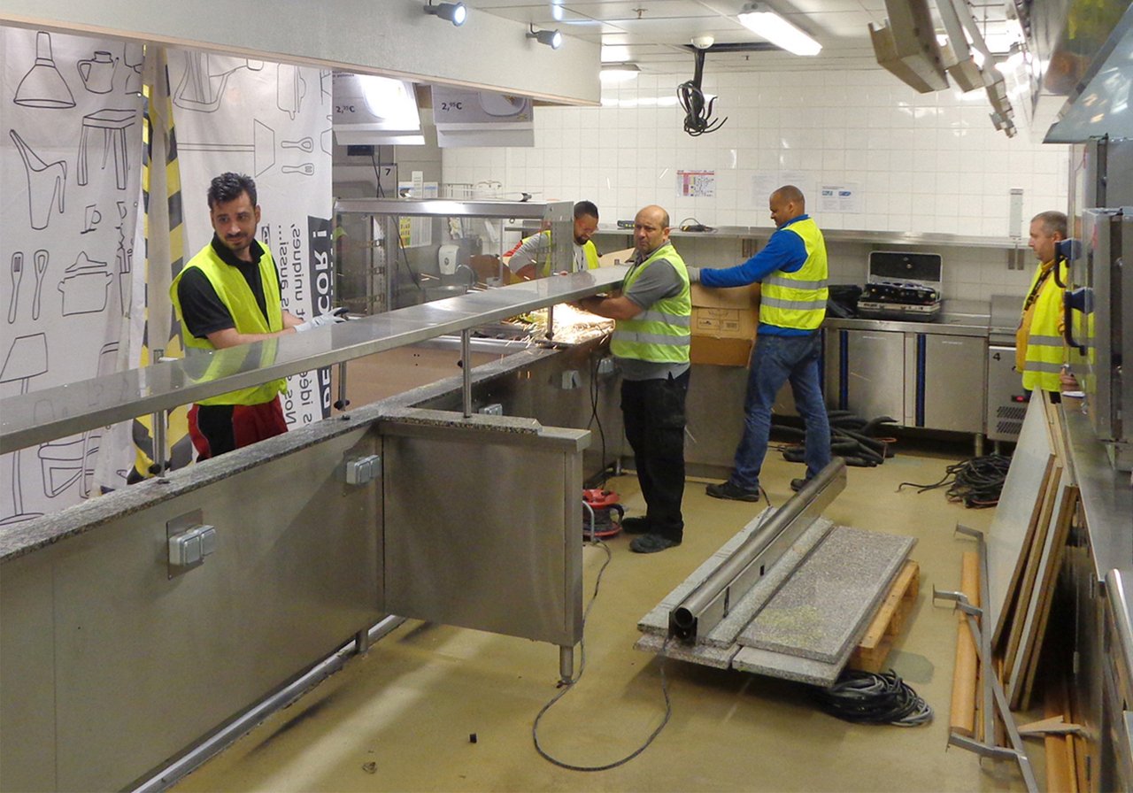 Five kitchen installation technicians install a preparation counter