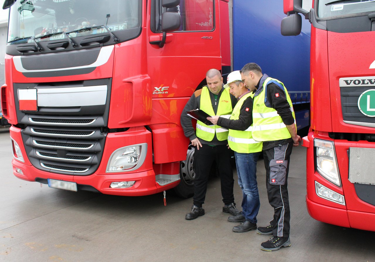 Two drivers outside their trucks receive instructions before departing