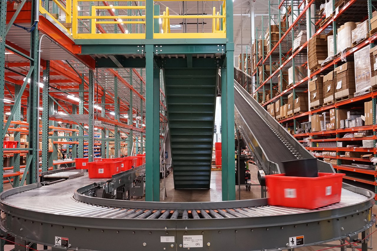 A double-level order conveyor system routes totes down a long ramp and around a tight curve 