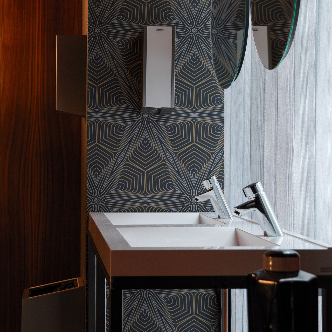 Modern bathroom with a patterned wall, rectangular sink, and chrome Franke faucets