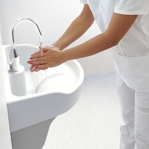 Doctor washes her hands in hygiene sink