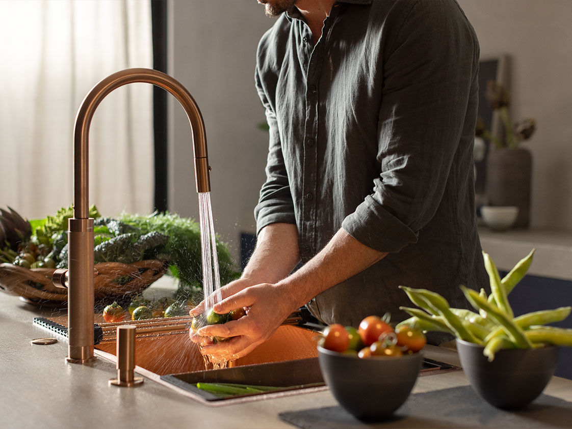 Man using Franke kitchen tap to wash vegetables