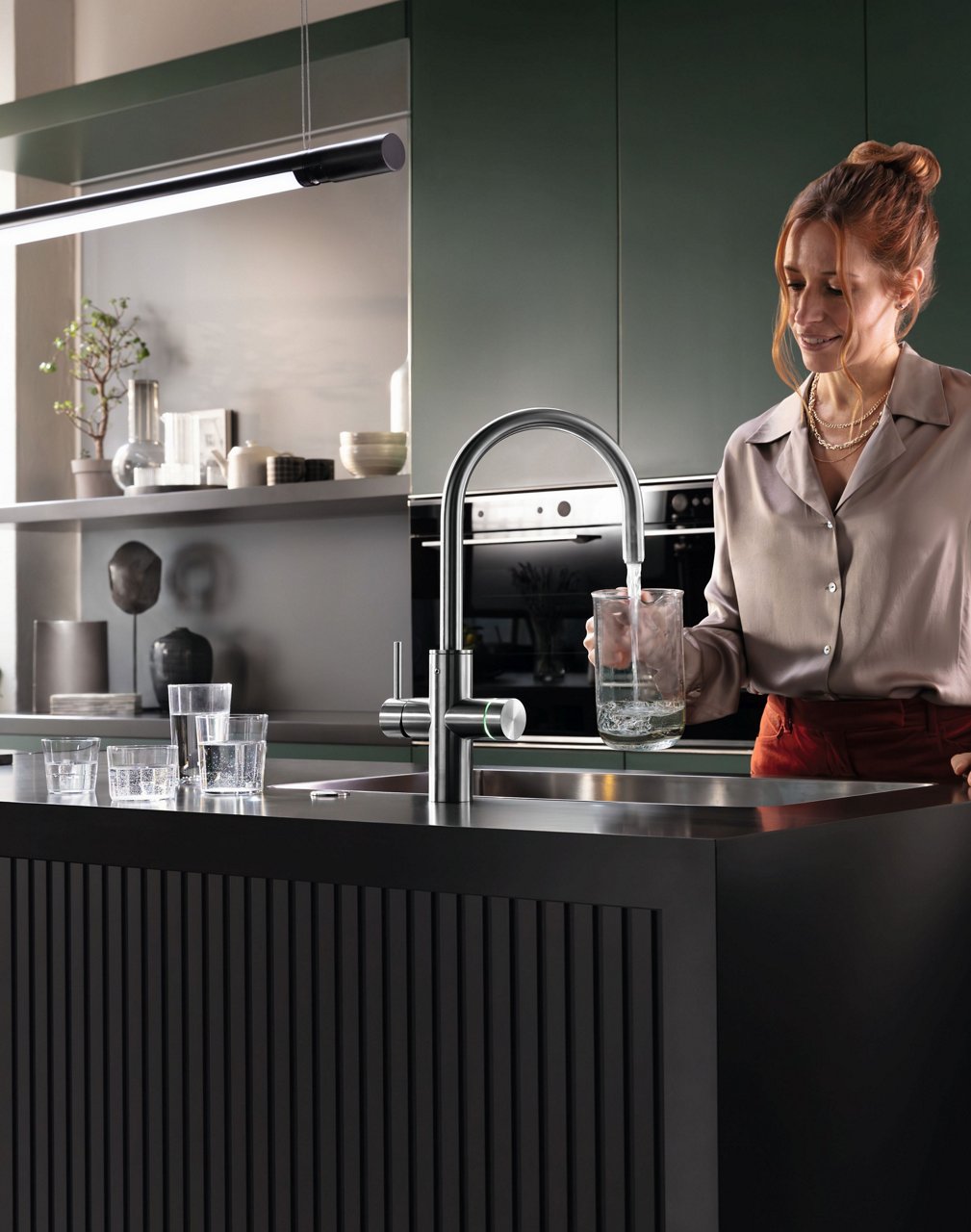 Una donna in cucina riempie una brocca di acqua filtrata
