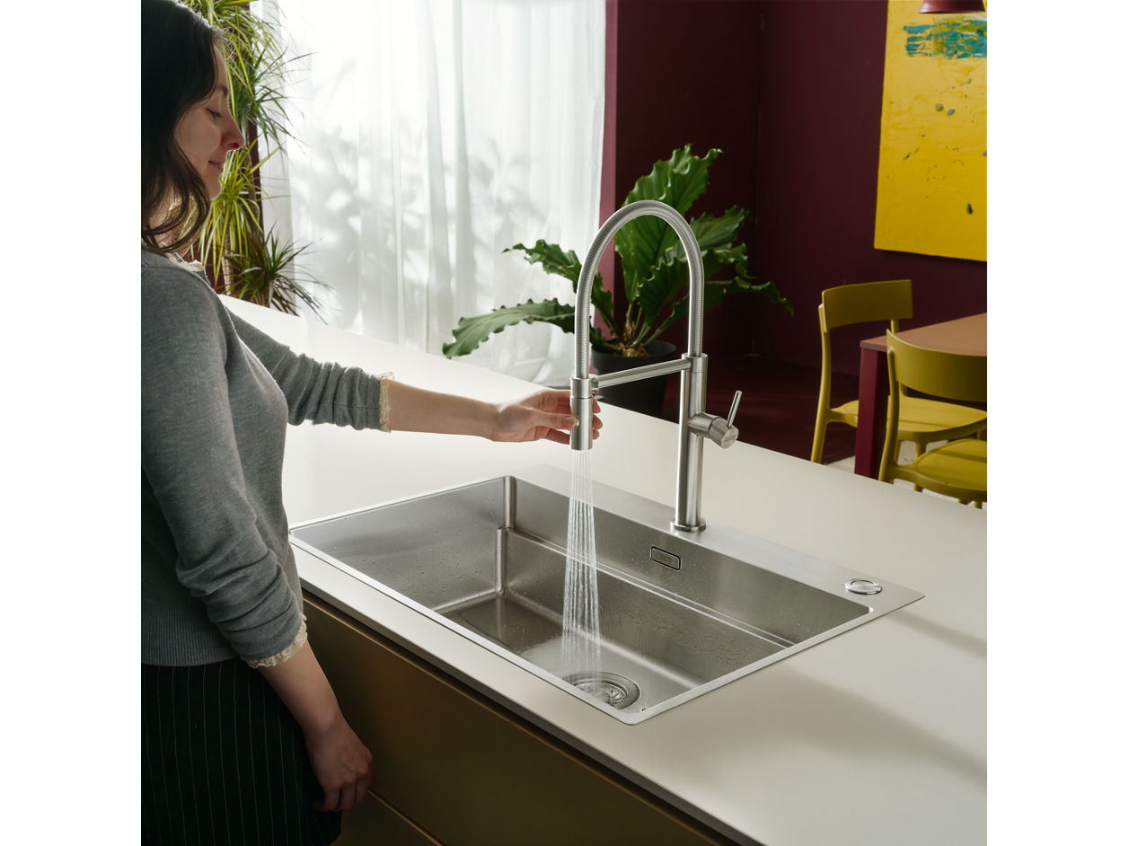 Family chopping fruits with accessories on a franke stainless steel sink