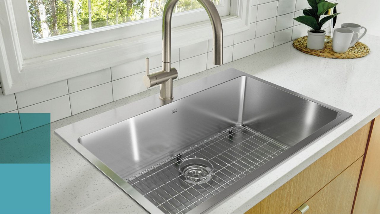 Top down view of a Kindred Brookmore single bowl stainless sink with a bottom grid and a chrome pull down faucet