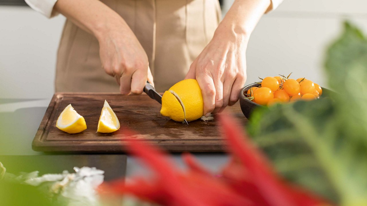 Someone chopping lemons on a wooden chopping board