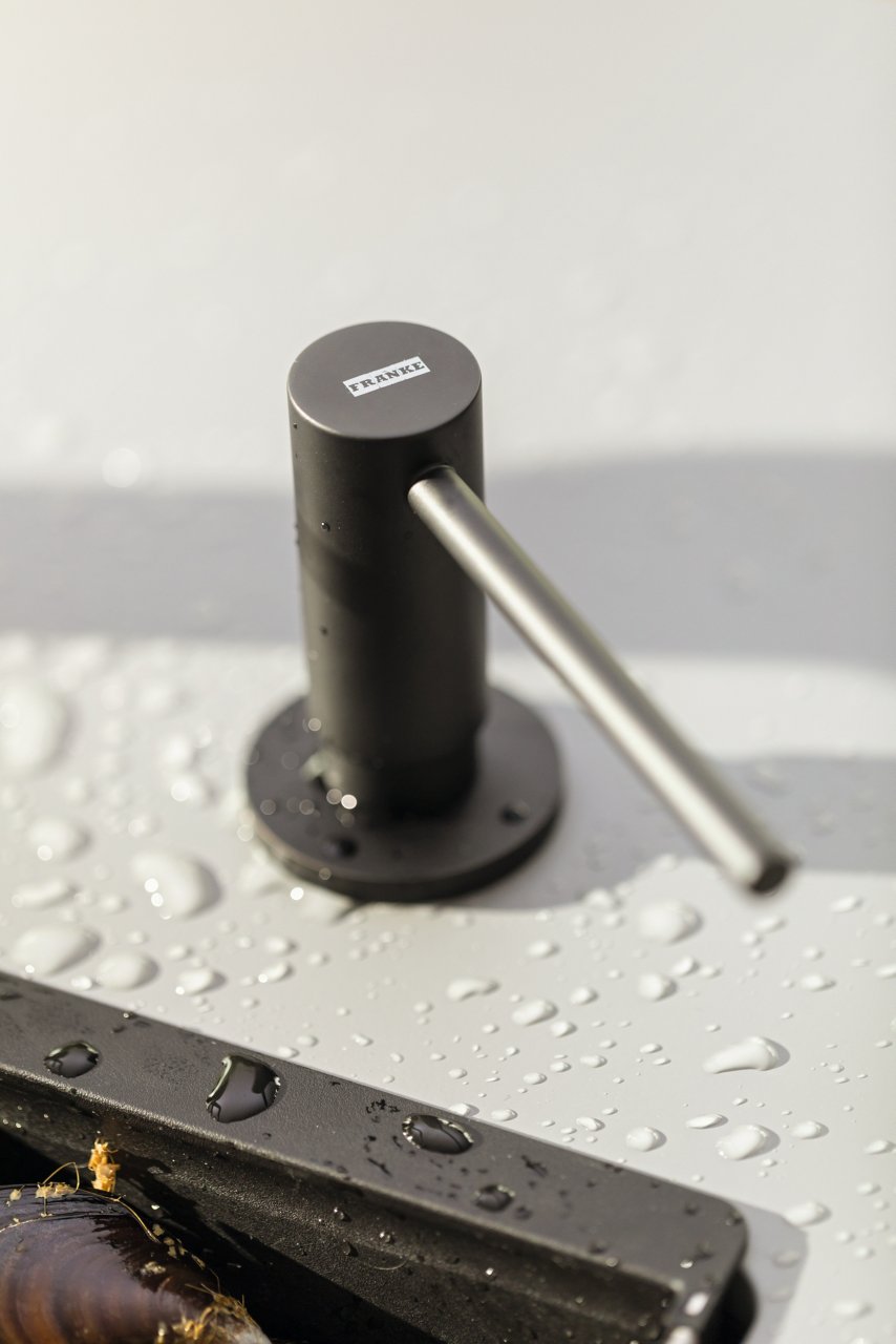 Czarny dozownik Franke, zamontowany na blacie kuchennym z widocznymi kroplami wody.