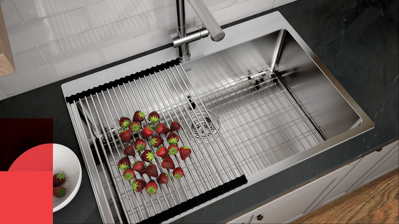 Strawberries being rinsed on a roller mat over a stainless steel drop in single bowl kitchen sink