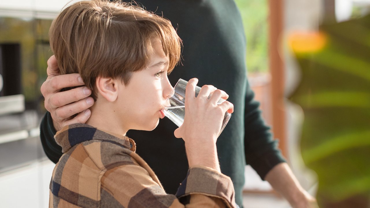 Жінка п'є чисту воду зі склянки