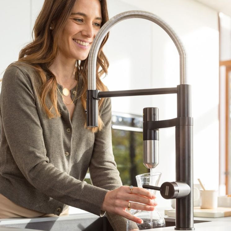 Vrouw neemt water van een filterkraan in de keuken