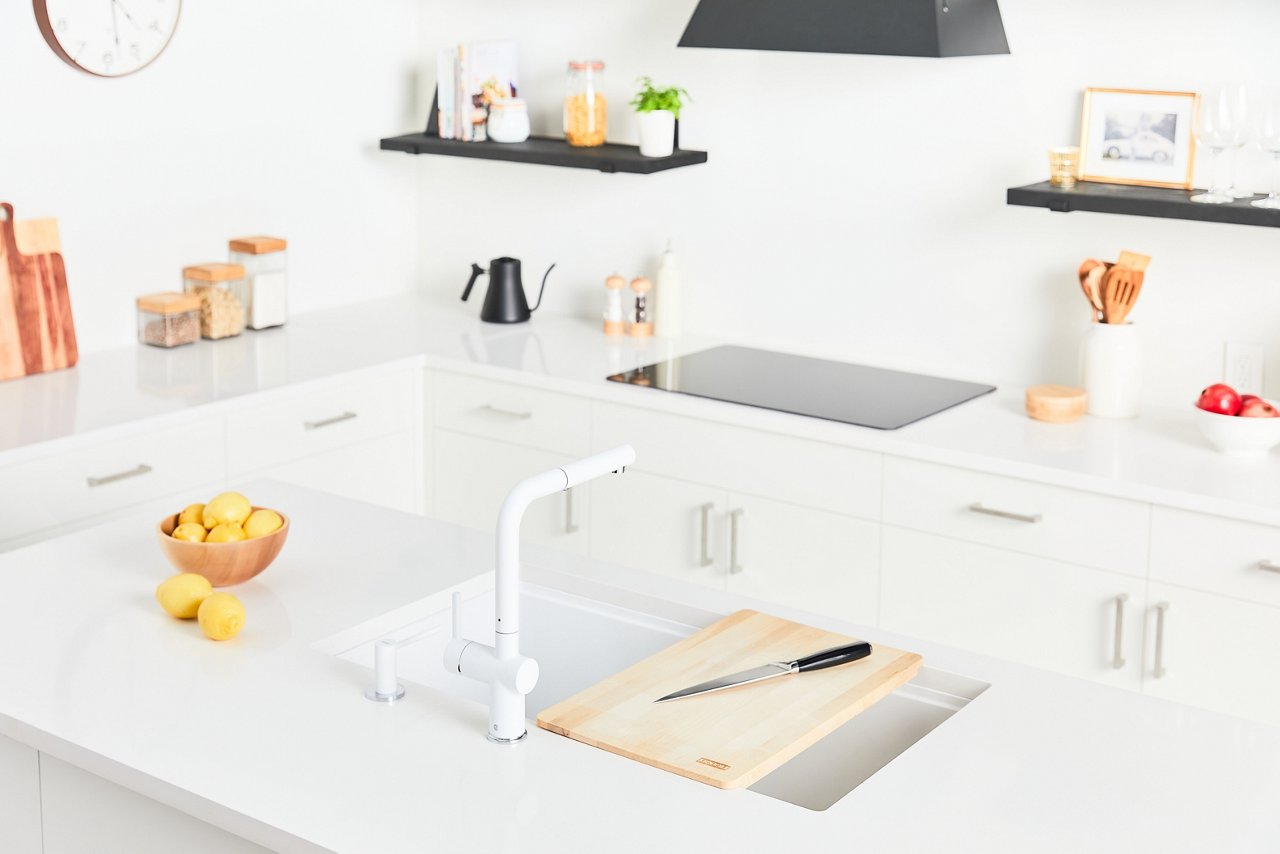 Bright white modern kitchen featuring a polar white Franke Maris sink and polar white Active faucet in a white kitchen island 