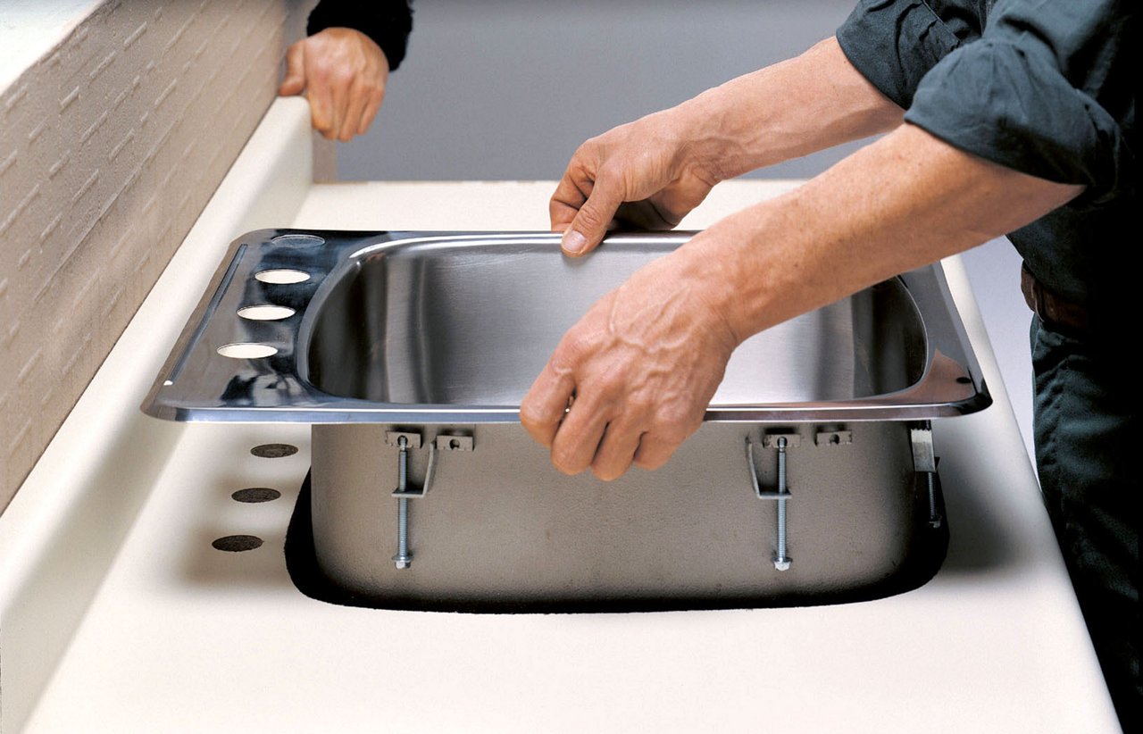 mans hands dropping single bowl sink into countertop