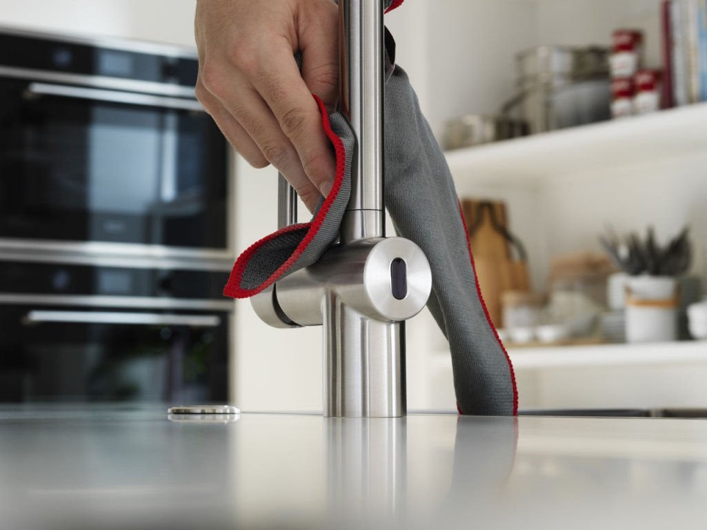 Someone cleaning a tap with a microfibre cloth