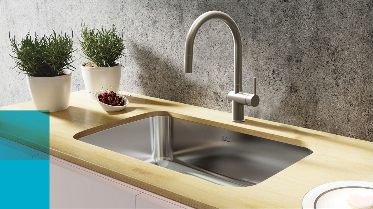 Close up of a Kindred single bowl stainless steel undermount kitchen sink and stainless steel faucet in butcher block counter top