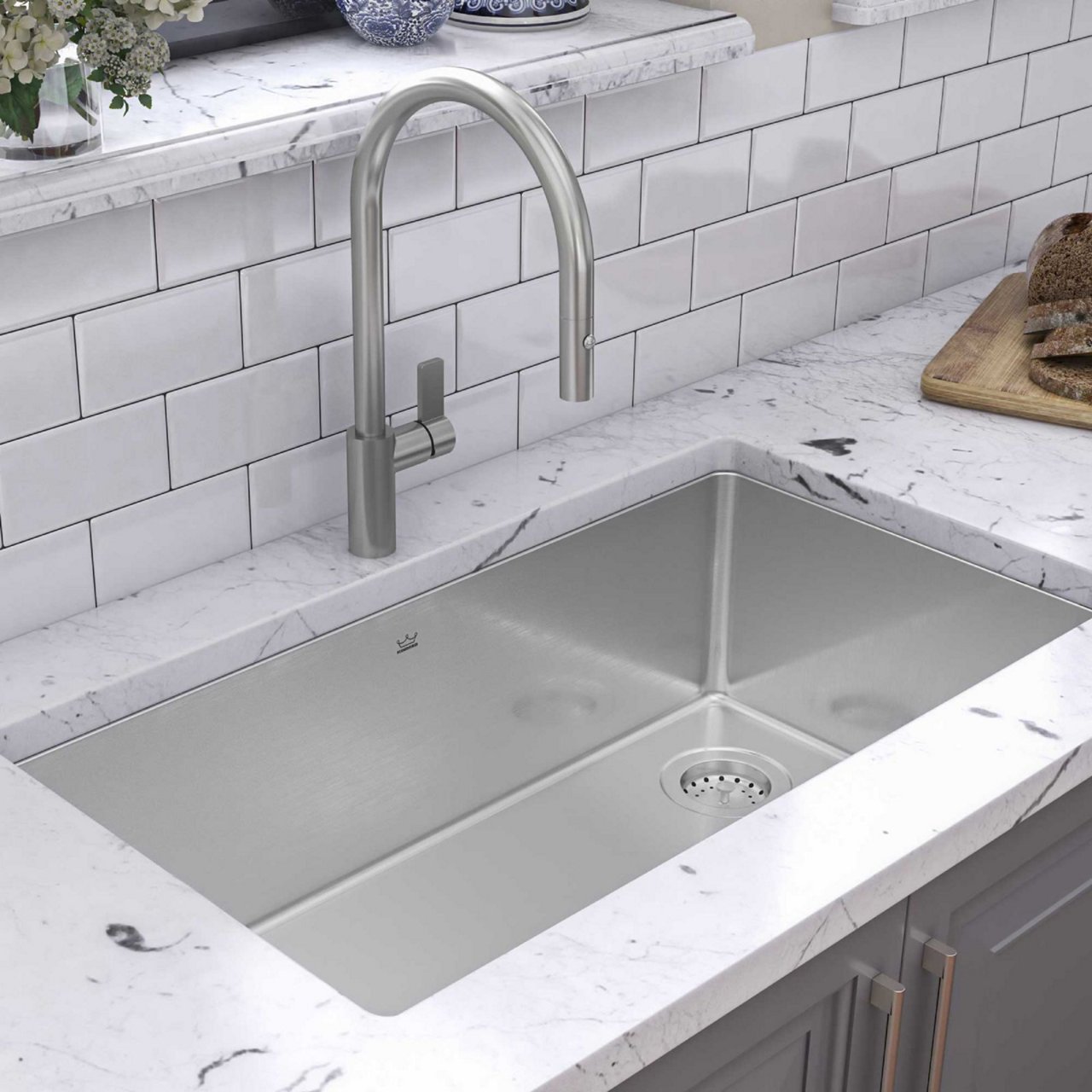 Close up of a Kindred undermount single bowl kitchen sink with stainless steel faucet