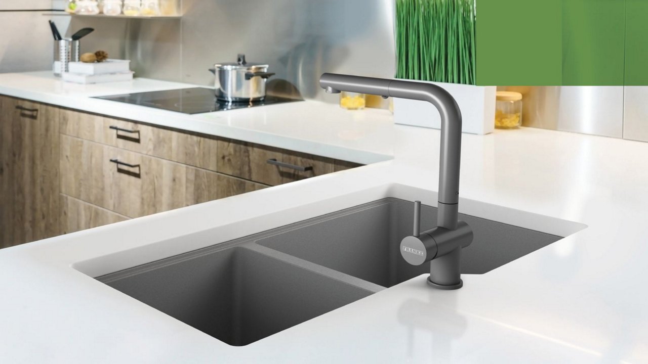 Kindred grey double bowl granite kitchen sink with a matching grey faucet in a white countertop 